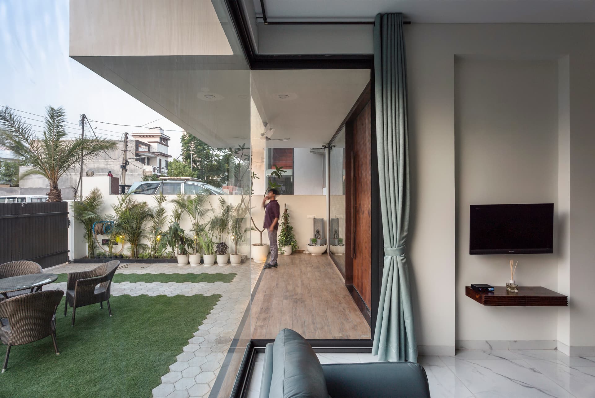 Living room view to landscaped garden, large glass walls inviting sunlight, and wooden deck enhancing the indoor-outdoor connection seamlessly.