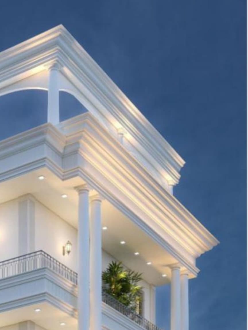 A detailed neoclassical crown paired with slender double columns creates a refined, symmetrical façade that highlights the building’s elegant architectural character