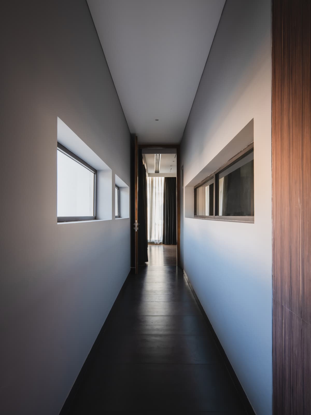 Minimalist corridor with sleek flooring, horizontal windows, and clean lines emphasizes linearity, natural light, and functional spatial transition.