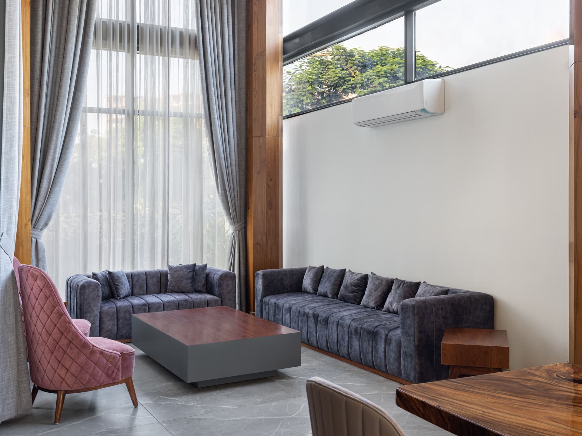 Double-height seating area with soft furnishings, natural light filtering through full-height curtains, and clean detailing highlighting contemporary residential sophistication.
